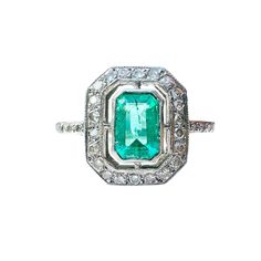 A stunning Art Deco style, Emerald and diamond ring, featuring an Emerald, mounted in a collet setting, surrounded with a row of twenty-two, eight cut diamonds, all beautifully made in Platinum with diamond mounted shoulders terminating to a slender shank. The Emerald is a beautiful green coloured gemstone, it is an emerald-cut and measures 6.5 x 4.7mm with an estimated carat weight of 0.65cts The diamonds are eight-cuts, they are bright and clean with an estimated combined carat weight of 0.28c Art Deco Diamond Emerald Ring Octagon Shape, Classic Octagon Emerald Ring With Diamond Accents, Classic Emerald Ring With Diamond Accents And Octagon Shape, Fine Jewelry Octagon Ring With Single Cut Diamonds, Art Deco Emerald Cut Diamond Ring With Halo Setting, Art Deco Diamond Ring With Gemstone, Classic Octagon Emerald Ring With Halo Setting, Art Deco Emerald Diamond Ring With Accents, Art Deco Emerald Ring With Diamond Center Stone