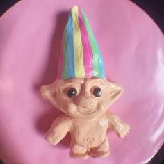 there is a small toy that looks like a troll on a pink plate with a black background