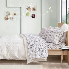 a bed with white comforter and pillows in a bedroom next to a large window