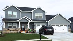 a black truck parked in front of a gray house with two garages on each side