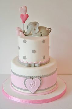 a baby elephant is sitting on top of a cake with pink and gray trims