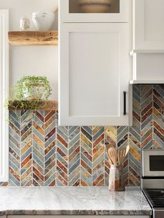 a kitchen with white cabinets and colorful tiles on the backsplash, along with wooden utensils