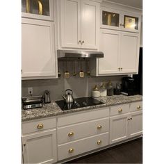 a kitchen with white cabinets and gold pulls on the cupboards is pictured in this image