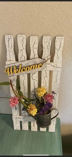 a welcome sign sitting on top of a wooden chair with flowers in front of it