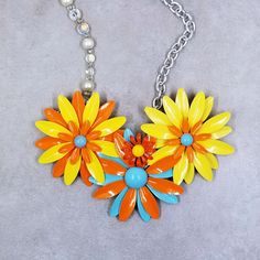 This handcrafted enamel flower necklace brings instant sunshine with its bright yellow, orange and blue colors. Vintage enamel flower brooches from the 1950s have been repurposed into this one of a kind assemblage necklace. Brighten up your  wardrobe with this great one of a kind necklace. As with all vintage items, some evidence of wear is to be expected. It is, however, in excellent vintage condition! Please do inspect the pictures. If you prefer items with a past repurposed for the present, m Vintage Handmade Flower Shaped Necklaces, Vintage Handmade Flower Shape Necklaces, Handmade Vintage Flower Shape Necklaces, Vintage Handmade Flower Shaped Necklace, Handmade Vintage Necklace With Flower Shape, Vintage Multicolor Flower Jewelry, Vintage Yellow Enamel Jewelry, Multicolor Flower-shaped Vintage Jewelry, Vintage Multicolor Jewelry With Flower Charm