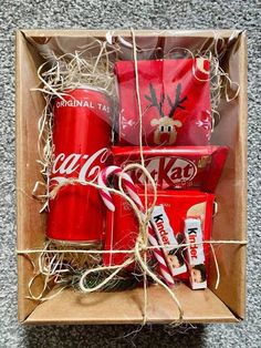 an open box filled with coca - cola cans and wrapped in twine, sitting on the floor