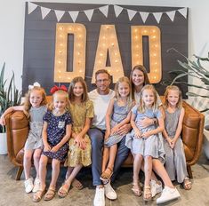 a family sitting on a couch in front of a sign that says dad