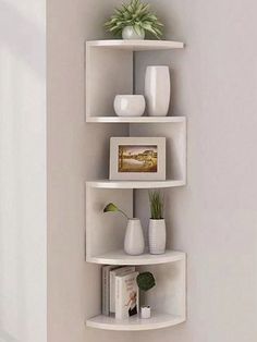 three white shelves with plants and vases on them in the corner of a room