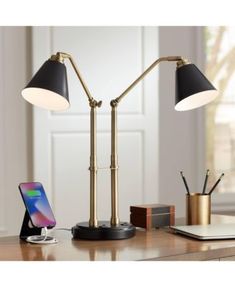 a desk lamp sitting on top of a wooden table next to a laptop and phone