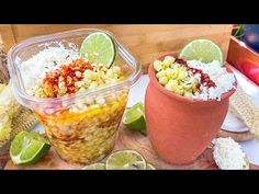 two plastic containers filled with food sitting on top of a wooden cutting board next to limes