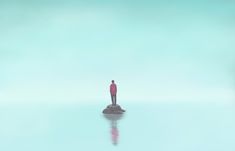 a man standing on top of a rock in the middle of water