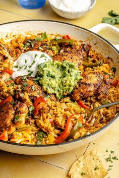 a pan filled with rice, meat and veggies next to tortilla chips