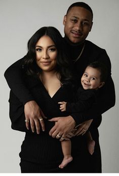 a man and woman holding a baby in front of a white background with the caption's name on it