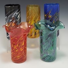 four different colored glass vases sitting next to each other