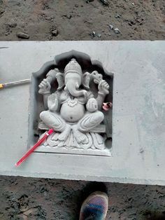 a person standing in front of a cement statue with a red arrow sticking out of it