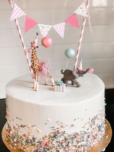 a birthday cake decorated with animals and balloons