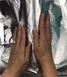 two hands reaching out towards each other over aluminum foil