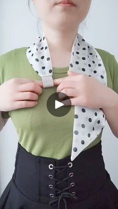 a woman wearing a green shirt and black skirt with white polka dots on the collar