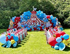 a circus themed birthday party setup with balloons and tableware on the grass in front of an outdoor tent