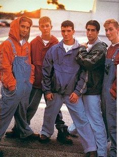 a group of young men standing next to each other in front of a plane at an airport