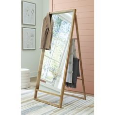 a large mirror sitting on top of a wooden floor next to a wall mounted coat rack