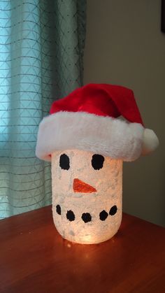 a light up snowman hat sitting on top of a wooden table next to a window