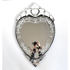 a woman taking a selfie in front of a heart shaped mirror with her reflection