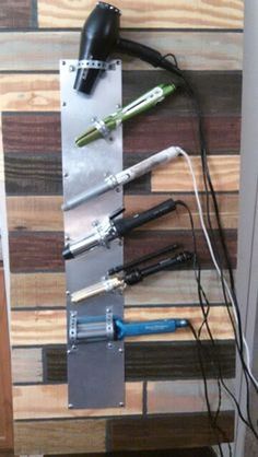 several different types of hair dryers on a wooden shelf with wires attached to it