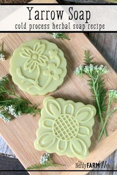 two homemade soaps sitting on top of a cutting board next to flowers and herbs