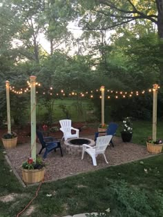 an outdoor patio with chairs and lights strung over it, surrounded by trees in the background