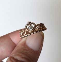 a hand holding a gold ring with a diamond in it's center and filigrees around the band