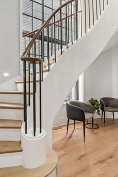 a white staircase with two chairs and a plant in the corner on the far side