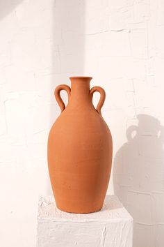 a brown vase sitting on top of a white block