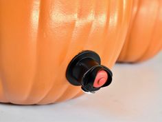 two orange pumpkins sitting side by side on a white surface with black knobs