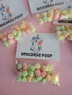 four bags filled with unicorn themed candy sitting on top of a pink table next to each other