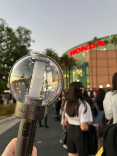 a person is holding a light in front of a building with people walking around it