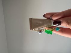 a person holding onto a small tube with charms on it's end and a chain attached to it