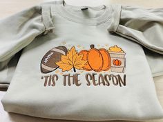 Made-to-order Soft and Cozy Fall Sweatshirt. Celebrate the coziest season in style with our Embroidered Fall Sweatshirt. This soft and comfy sweatshirt is made to order with fast shipping. Perfectly captures the essence of Autumn with vibrant and delightful colors featuring Football, Fall Leaf, Charming Pumpkin and a Pumpkin Latte. Whether you're cheering your favorite team or enjoying a crisp fall day, this sweatshirt is your go to for seasonal comfort.  Sweatshirts: High quality fleece  *Crewneck 9 oz., 50% cotton, 50% polyester *Hoodie: 8 oz., 50% cotton, 50% polyester  oHeather Sport colors are 60% polyester, 40% cotton T-shirts: 100% Preshrunk Cotton *5.3 oz., 100% preshrunk cotton *Ash Grey is 99% cotton, 1% polyester *Antique (Cherry Red, Jade Dome, Irish Green, Sapphire, Orange) an Cozy Fall Sweatshirt With Letter Embroidery, Cozy Sweatshirt With Letter Embroidery For Fall, Cozy Letter Embroidery Sweatshirt For Fall, Fall Sweatshirt For Loungewear With Embroidered Text, Fall Loungewear Sweatshirt With Embroidered Text, Wreath Sash, Red Jade, Pumpkin Latte, Fall Leaf