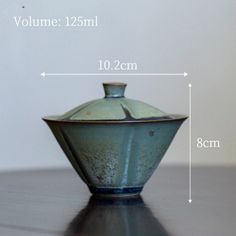 a blue vase sitting on top of a wooden table next to a white wall with measurements