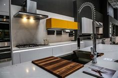 a kitchen with white counter tops and yellow accents on the cabinets, along with a cutting board