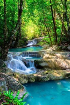 a river running through a lush green forest filled with lots of rocks and water flowing down it