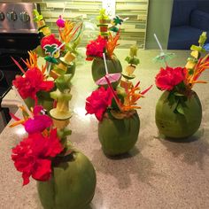 four green vases with flowers in them sitting on a counter top next to a stove