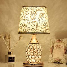 a lamp sitting on top of a table next to a small vase with flowers in it