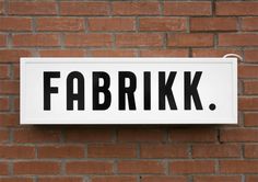 a white sign mounted to the side of a brick building that says fabrik