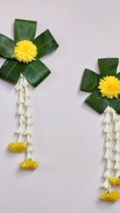 two pieces of paper with flowers and leaves attached to them on a white wall background