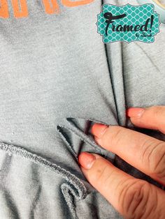 a woman's hand is stitching through the pocket of her gray hoodie