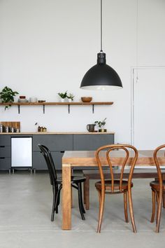 a dining room table with chairs and shelves on the wall