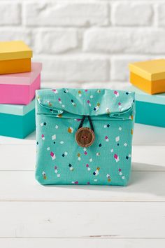 a small blue bag sitting on top of a table next to colorful books and a brick wall