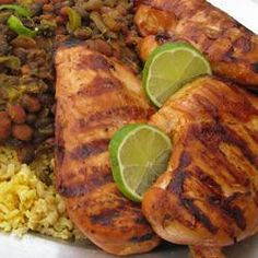 chicken, rice and beans on a plate with lime wedges