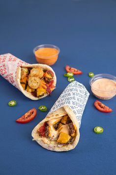 two burritos sitting on top of a blue table